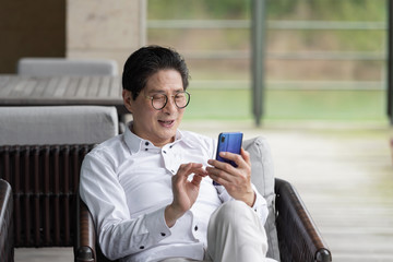 An Asian elderly man sitting on an outdoor chair