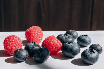 juicy fresh berries blueberries and raspberries are on the white table