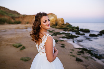 Fototapeta na wymiar Young bride wearing beautiful wedding dress on the tropical beach. Happy young bride woman in white dress running, have fun on clean sandy beach waves of azure sea or ocean on sunset, summer vacation
