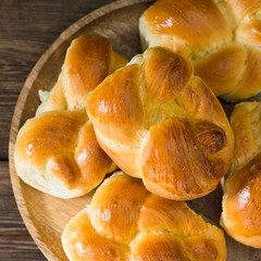 Buns on a wooden plate on a brown wooden table. Rustic pastries. Rustic style. The view from the top