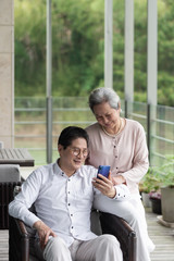 An Asian elderly couple sitting on an outdoor chair