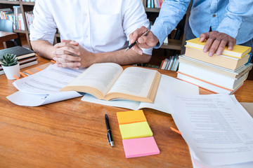 Teaching helping and study course, Team of young teacher or tutor helps students to learning in classroom for homework a test or exam at desk with papers