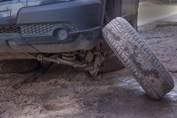 A broken wheel is standing next to the car. Old wheel hub. Emergency situation in a road The car...