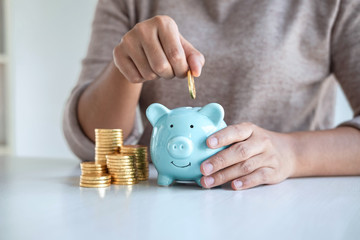 Young woman putting coins into piggy bank planning growing saving to strategy with money box for...