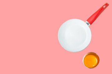 Breakfast ingredients cracked raw egg with bright yellow yolk frying pan on pink background. Culinary food poster with copy space