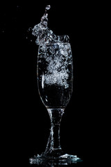 Splashes and drops of water in a glass are isolated on a black .