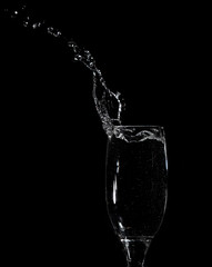 Splashes and drops of water in a glass are isolated on a black .