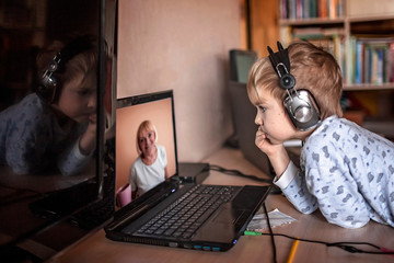 Cute boy talking with his grandmother within video chat on laptop, life in quarantine time