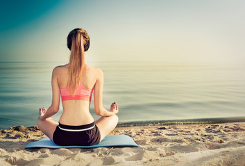 Fototapeta na wymiar woman meditating on the beach