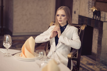 A young businesswoman in casual clothes, sitting in a luxury apartment and thinking, making an important decision.