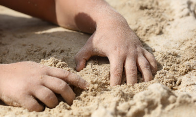 A boy is playing in the sand of a beach.