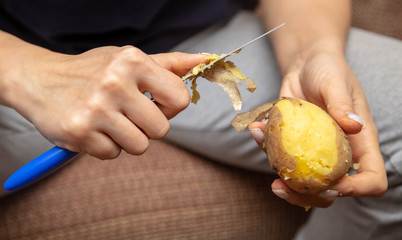 Girl peeling boiled potatoes with a knife