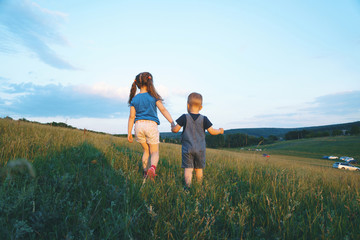 sister and brother holding hands in field