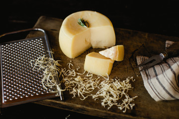 delicious cheese wheel grated on dark background.