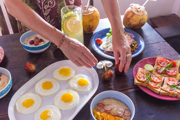 Women hands holding forks and spoons and picking spicy Thai food dinner on wooden table.