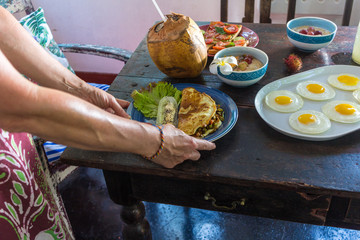 Women hands holding forks and spoons and picking spicy Thai food dinner on wooden table.