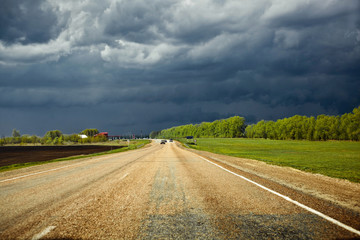 road in the field with storm clouds