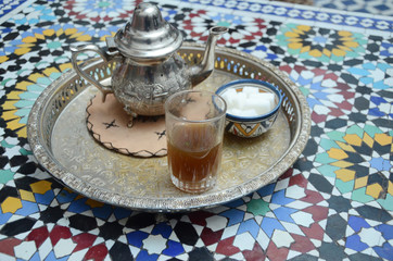 Moroccan tea with mint and sugar in a glasses on a copper plate with kettle