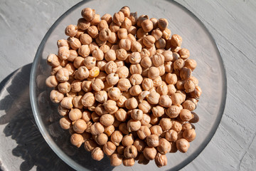 chickpea in a glass bowl on a grey table top view with sun flare and hard shadow. Healthy dietary food concept

