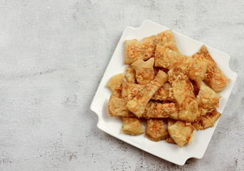 Puff pastry cheese straws on a white rectangular plate on a light gray background. Top view, flat...