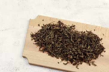 Raw green herbal organic tea on a wooden cutting board on a light gray background. Top view, flat lay