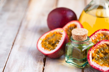 Passion fruit and its oil in glass bottle. Natural organic essence. White wooden background. Close up macro copy space for text