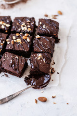 Chocolate brownie with nuts on paper on white background
