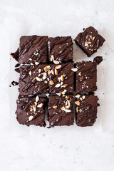 Chocolate brownie with nuts on paper on white background
