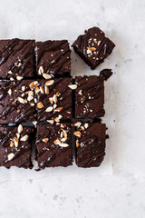 Chocolate brownie with nuts on paper on white background