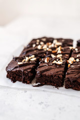 Chocolate brownie with nuts on paper on white background
