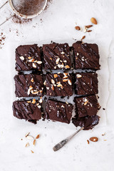 Chocolate brownie with nuts on paper on white background