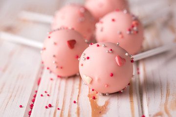 Dessert on a stick. Pink cake pops with a sprinkle on a wooden background.