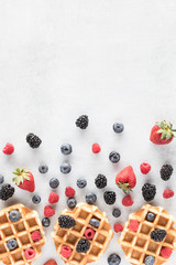 Top down view of Belgian waffles with berries in an abstract arrangement.