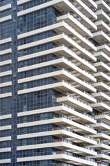 Fototapeta premium Glass blue square Windows of facade modern city business building skyscraper. Balconies in the building. Modern apartment buildings in new neighborhood. Abstract architecture. Texture.