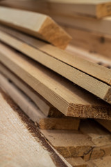 Stack of natural brown uneven rough wooden boards on building site. Industrial timber for carpentry, building