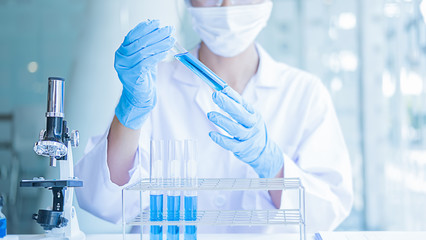 Fototapeta premium Medical or scientific researcher or man doctor looking at a test tube of clear solution in a laboratory