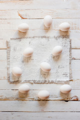 White chicken eggs lying on a white painted wooden surface. Background for livestock products.