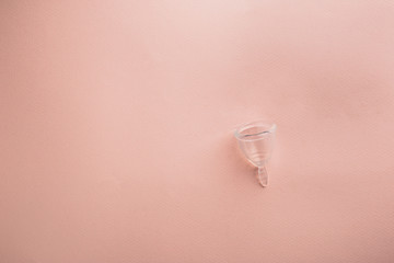Menstrual cup on pink background. Alternative environmentally friendly feminine hygiene product to collect blood during the period inside the vagina.