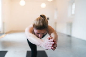 Fototapeta premium Beautiful young woman trains with yoga exercises in a white gym - Millennial in a moment of relaxation and personal well-being