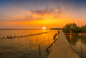Obraz premium Sunset over the lake in the village ,The bridge stretches out to sea and sunsets in the evening , 