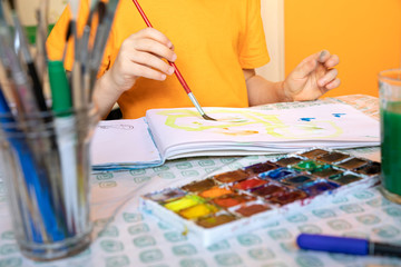 Naklejka premium drawing materials on blurred background and boy is painting. creative activities and leisure for children at home.