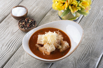 Delicious soup with cheese and meat in a restaurant on a white wooden table