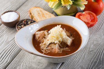 Delicious soup with cheese and meat in a restaurant on a white wooden table