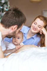 Fototapeta premium Three-month-old baby in the arms of happy young parents. The most touching moments with father and mother