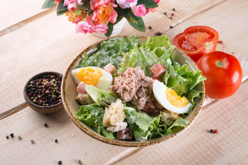 Fresh salad with greens, vegetables, onions and pepper stands on the table in the restaurant