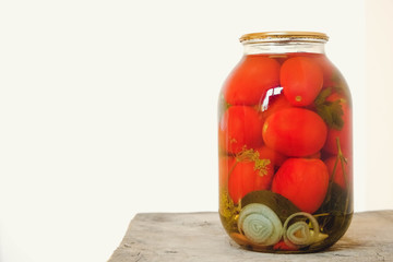 Pickled tomato in a glass jars on wooden table. Copy, empty space for text