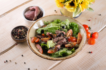 Fresh salad with greens, vegetables, onions and pepper stands on the table in the restaurant