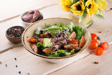 Fresh salad with greens, vegetables, onions and pepper stands on the table in the restaurant