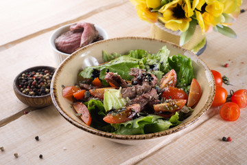 Fresh salad with greens, vegetables, onions and pepper stands on the table in the restaurant