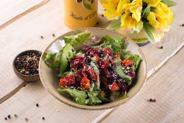 Fresh salad with greens, vegetables, onions and pepper stands on the table in the restaurant